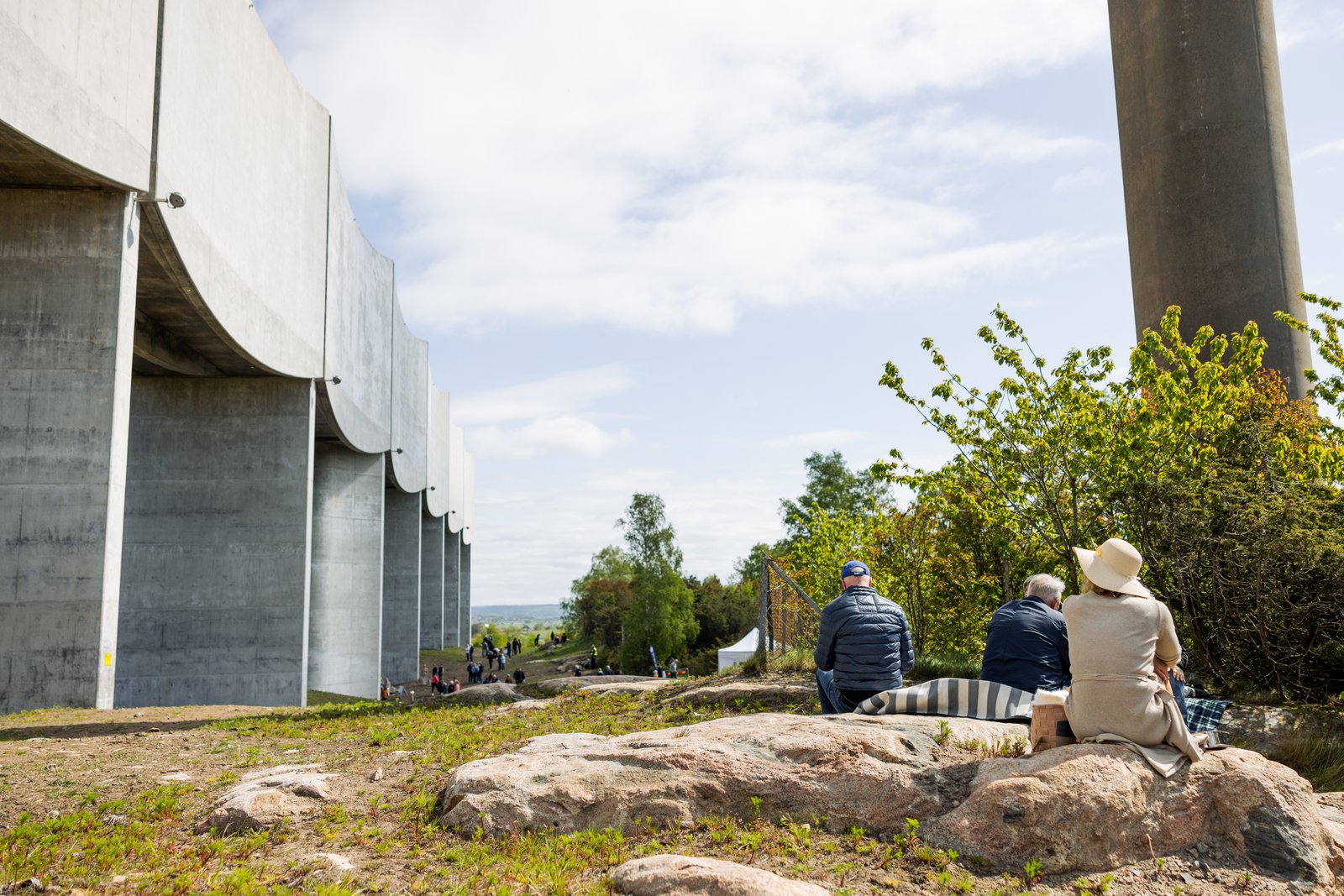 Några personer sitter i solen på stenar bredvid vattentornet Våga