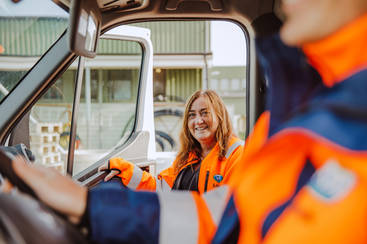 En person sitter vid ratten i en bil och en person är på väg att hoppa in på passagerarsidan.