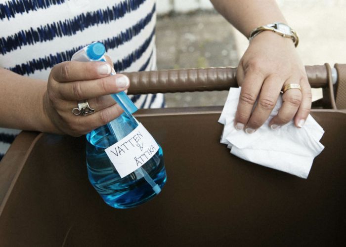 En person som sprayar ättikslösning på ett matavfallskärl