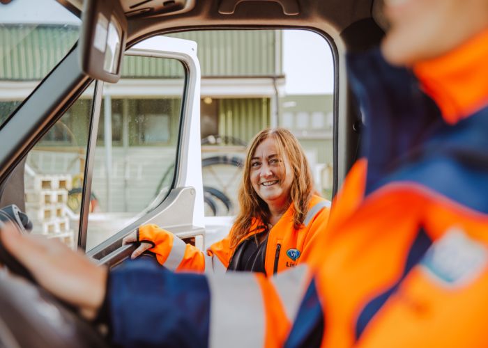 En person sitter vid ratten i en bil och en person är på väg att hoppa in på passagerarsidan.