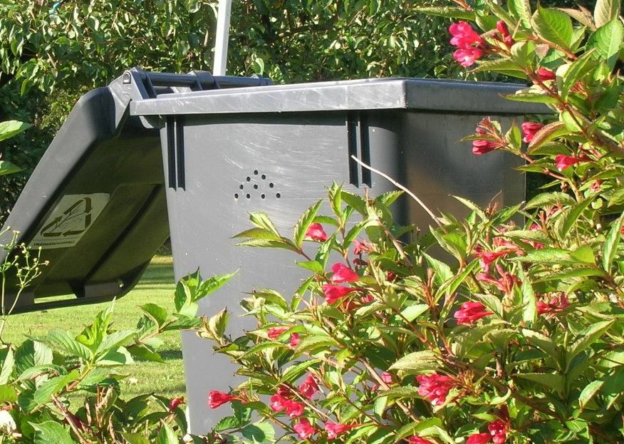 Ett grått trädgårdskärl står i en trädgård