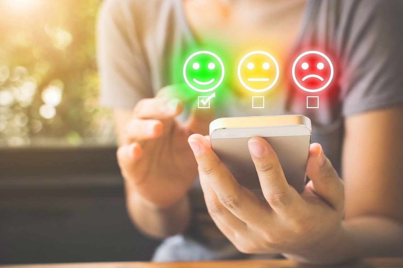 En kvinna har en mobiltelefon i handen och ska besvara en enkät med emojis