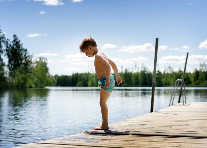 Ett barn som står på en brygga och tittar ner i vattnet